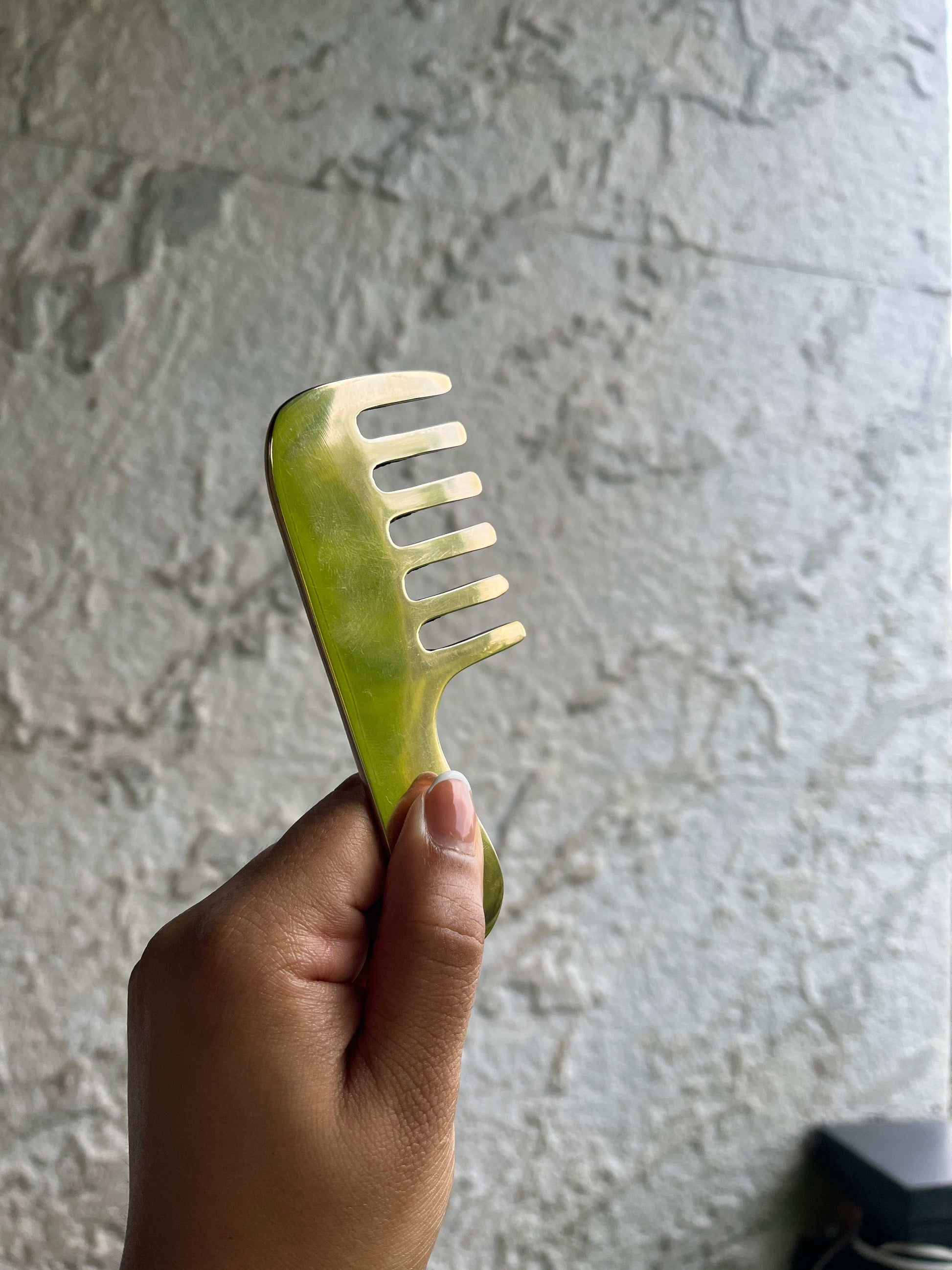 Kansa hair massage comb held in hand, promoting scalp circulation with Ayurvedic care